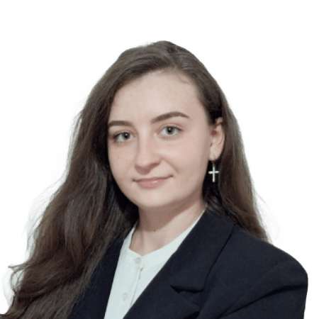 O femeie cu părul lung și castaniu, purtând un blazer negru și un top alb, se uită la cameră, întruchipând esența expertizei profesionale SEO.