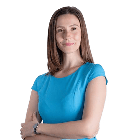 O femeie cu părul lung și castaniu stă încrezătoare cu brațele încrucișate, purtând un top albastru cu mâneci scurte, întruchipând esența expertizei SEO.