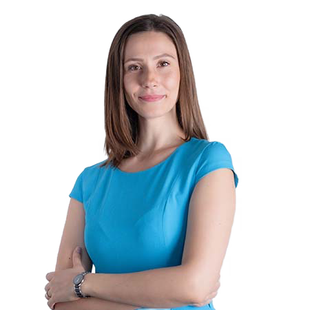 O femeie cu părul lung și castaniu stă încrezătoare cu brațele încrucișate, purtând un top albastru cu mâneci scurte, întruchipând esența expertizei SEO.