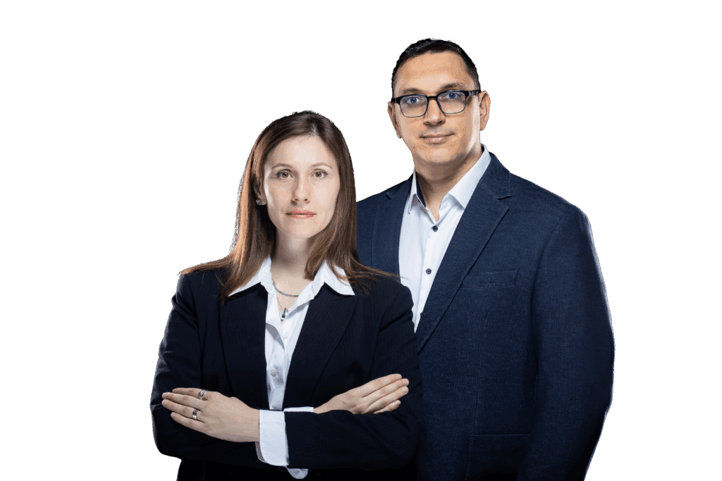 Două persoane în ținută business stau una lângă alta pe un fundal alb, reprezentând cu încredere Servicii SEO București, în timp ce persoana din față stă cu brațele încrucișate, privind direct la cameră.